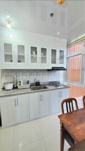 a kitchen with white cabinets and a wooden table at Baguio Condo Transient Grand View Unit314 by Dei Gratia in Baguio