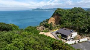 南淡路市amarancia cottage hugging nature house的靠近海洋悬崖的建筑物的空中景观