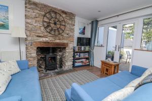 ein Wohnzimmer mit einem blauen Sofa und einem Steinkamin in der Unterkunft Armada Cottage in Dartmouth