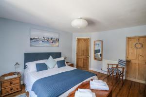 Schlafzimmer mit einem blauen und weißen Bett und einem Tisch in der Unterkunft Armada Cottage in Dartmouth