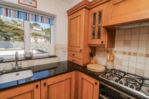 eine Küche mit Holzschränken, Spüle und Herd in der Unterkunft Armada Cottage in Dartmouth