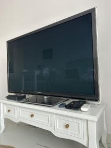 een grote flatscreen-tv zittend op een wit entertainment center bij GoldClass Apartament in Katowice