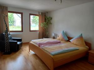 a bedroom with a bed and a chair and windows at Pension Espenhof 