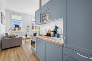 a kitchen with blue cabinets and a sink and a couch at HideOut Apartments in Brno