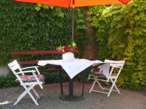a table and two chairs with an umbrella and flowers at SchlossparkFerienwohnungen Rheinsberg in Rheinsberg