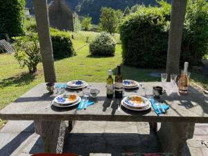 a picnic table with plates of food and wine bottles at A La Capeleta in Avegno