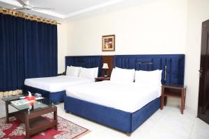 a hotel room with two beds and a table at Royalton Inn Hotel - Liberty in Lahore