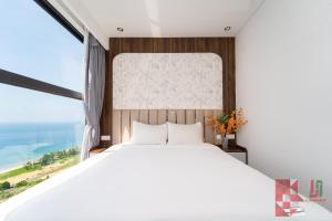 a bedroom with a large bed and a large window at Apec Mandala Mui Ne by LHG - Sea View, Infinity Pool, Alacarte, 17m to Bàu Trắng Bình Thuận in Mui Ne
