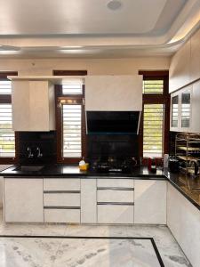 a large kitchen with white cabinets and black counter tops at Shanti vilas in Jaipur