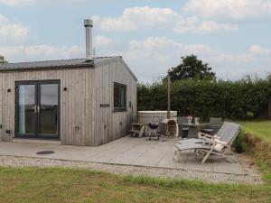 een klein schuurtje met een terras en een tafel en stoelen bij The Pennymoor in Tiverton