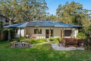 a house with a solar roof with a table and chairs at Salt and Stone Modern Pearl Beach Stay 2 Mins to Ocean in Pearl Beach