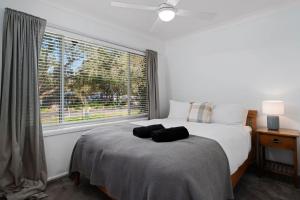 a bedroom with a bed and a large window at Salt and Stone Modern Pearl Beach Stay 2 Mins to Ocean in Pearl Beach