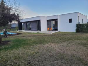 ein weißes Haus mit orangefarbenen Stühlen im Hof in der Unterkunft Casa con piscina en Condominio Lago Rapel BLQ in El Estero