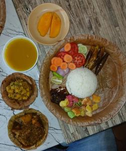 a table with a plate of food with rice and fruit at Jonaki Homestay in Jhārgrām