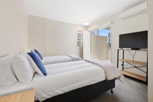 a bedroom with two white beds and a flat screen tv at Park View Apartment in Mantra Salt Resort by uHoliday - 2BR, 1BR and Hotel Room configurations available in Kingscliff