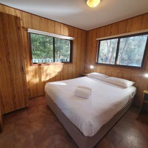una camera con letto bianco e pareti in legno di Pleasurelea Tourist Resort & Caravan Park a Batemans Bay