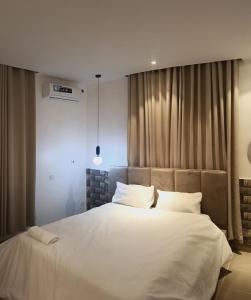a bedroom with a large bed with white sheets and pillows at Delight Apartment in Ikeja