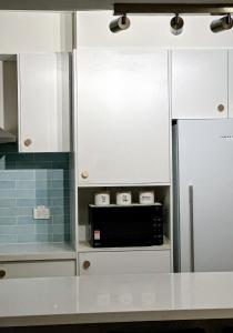 een keuken met witte kasten en een zwarte magnetron bij Chic Malvern Retreat, Ideal for Study, Relaxation, Fun in Melbourne