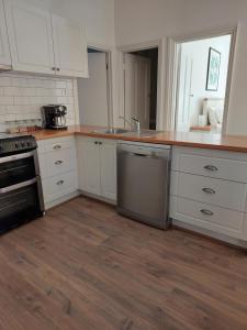 a kitchen with white cabinets and a wooden floor at Vivian's Rest in Castlemaine +8 photos