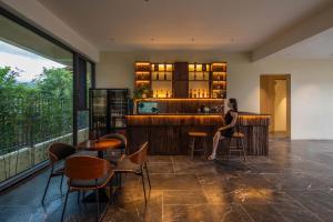 eine Frau, die an einer Bar in einem Restaurant sitzt in der Unterkunft Sunny Aerie丨 Golden Peak Resort in Baisha