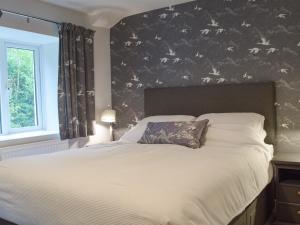 a bedroom with a bed with a bird wallpaper at Castle Street Cottage in Narberth +10 photos