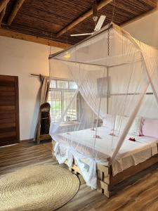 a bed in a room with a mosquito net at Jumanji B&B in Kinyasini