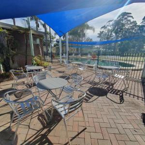 un gruppo di tavoli e sedie sotto un ombrellone blu di Pleasurelea Tourist Resort & Caravan Park a Batemans Bay
