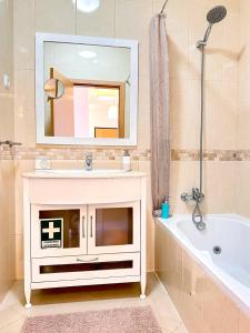 een badkamer met een wastafel, een bad en een spiegel bij AlbufeiraOrada Garden by Be Cherish in Albufeira