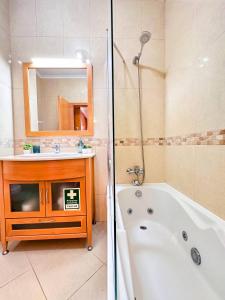 un bagno con vasca, lavandino e specchio di AlbufeiraOrada Cozy&Sunny Condo by BeCherish ad Albufeira