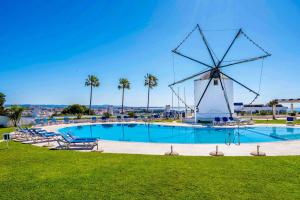 un mulino a vento accanto a una piscina con mulino a vento di Stunning Sunrise & Sunset Rooftop Condo by BeCherish ad Albufeira