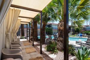a patio with chairs and a pool with palm trees at Papago Scottsdale by Reside, Trademark Collection by Wyndham in Scottsdale