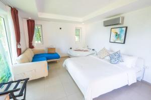 a white bedroom with a bed and a couch at Coral Cove Beachfront Villa - Koh Chang in Ko Chang