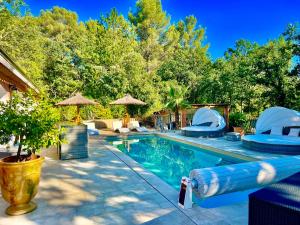 a swimming pool with chairs and umbrellas at La Casa dei Sogni in Flayosc