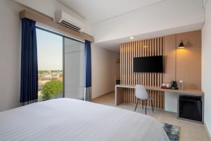 Una habitación de hotel con una cama, un escritorio y un televisor. en Aston Inn Lumajang - East Java, en Lumajang