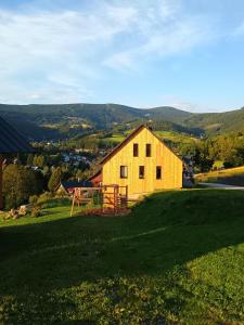 a yellow barn on a hill with a green field at Výhledovka chalet in Rokytnice nad Jizerou