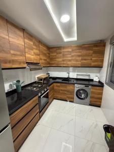 a kitchen with wooden cabinets and a stove top oven at Appart Résidence Sabrin in Fnidek