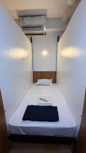 a small room with a white bed with a book on it at Ith Pods & Dormitory in Kozhikode