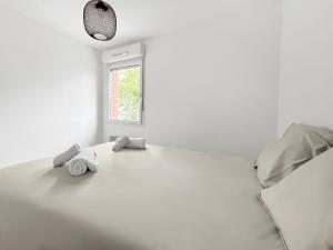 ein weißes Zimmer mit einem Bett und einem Fenster in der Unterkunft Joli appartement avec balcon, parking - Toulouse in Plaisance-du-Touch