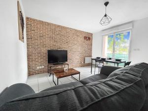 a living room with a couch and a brick wall at Appartement Aux Portes de Toulouse in Plaisance-du-Touch