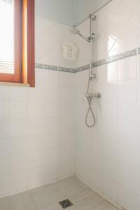 a bathroom with a shower with white tiles at Redlands House - casa vacanze in Uggiano la Chiesa