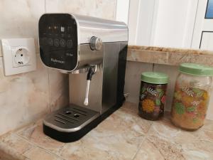 a coffee maker on a counter next to two jars at Studio Garden City Center Pomorie in Pomorie