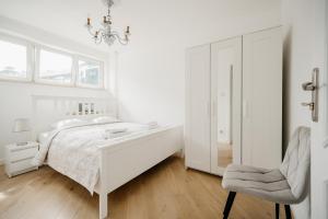 una camera da letto bianca con un letto e una sedia di Wita Stwosza Rynek Apartament Wrocław a Breslavia