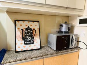 a kitchen counter with a microwave and a picture at Modern Suite In Bonifacio Global City in Manila