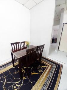 a dining room with a table and chairs on a rug at Perhentian Besut Homestay in Kuala Besut