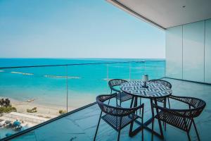 a glass balcony with a table and chairs and the ocean at Stunning 1 Bed in Trilogy, Limassol Seafront in Limassol
