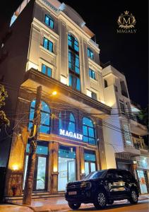 a car parked in front of a large building at Magaly Apartment & Hotel in Hai Phong