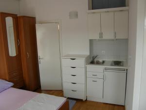 a small kitchen with white cabinets and a bed at Apartments Jakova Dudana 10 in Makarska