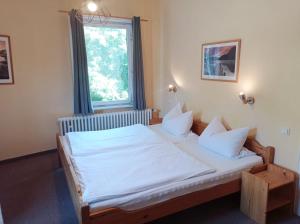 a bedroom with a bed with white sheets and a window at Pension Sonnenhof in Braunlage