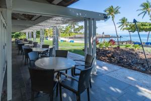 a row of tables and chairs on a patio with the beach at Mauna Lani Point Newly Furnished ocean golf views in Waikoloa