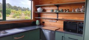 a kitchen with a counter with a microwave and a window at Murrells Manapouri Lookout in Manapouri